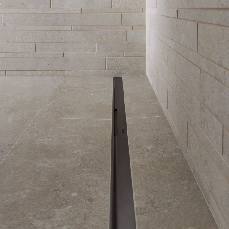 Vesi valuu viemäriin tyylikkään, ruostumattomasta teräksestä valmistetun muodon kautta. Vesi valuu viemäriin tyylikkään, ruostumattomasta teräksestä valmistetun muodon kautta.