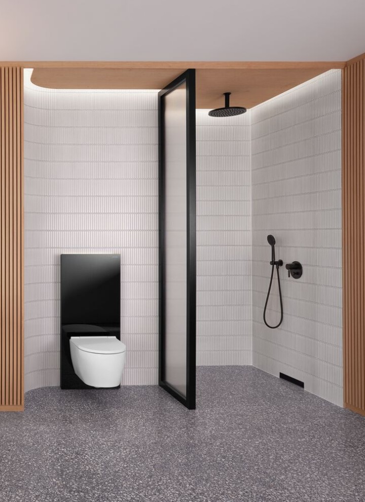 Kylpyhuone, jossa on puuseinä sekä mustavalkoinen suihku- ja WC-tila