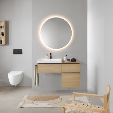 Kylpyhuone harmailla seinillä, Geberit-kylpyhuonekalusteet puusta ja pyöreä Geberit Option valaistu peili