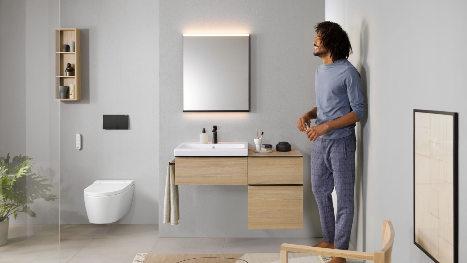 Man standing in a bathroom with an AquaClean Sela shower toilet. Toilets with bidet function look just like a normal toilet but have a range of comfort functions.
