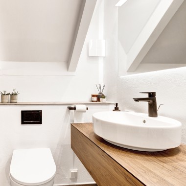 Uudistettu viistokattoinen kylpyhuone, musta huuhtelupainike ja musta pesuallashana (© @triner2 ja @strandparken3)