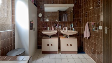 Kylpyhuone, jossa on ruskeat laatat ja kaksi pesuallasta