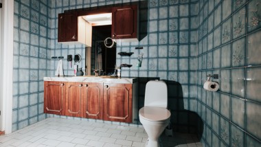 Kylpyhuone, jossa on siniset laatat ja lattiamallinen WC-istuin