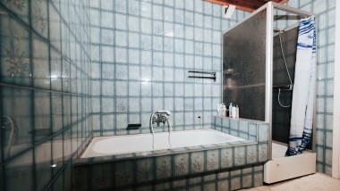 Kylpyhuone, jossa on siniset laatat, suihkukaappi ja kylpyamme
