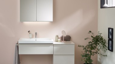 Pesupaikka, jossa on Geberitin kylpyhuonekalusteet, pesuallas ja peilikaappi pastellivärisellä seinällä. 