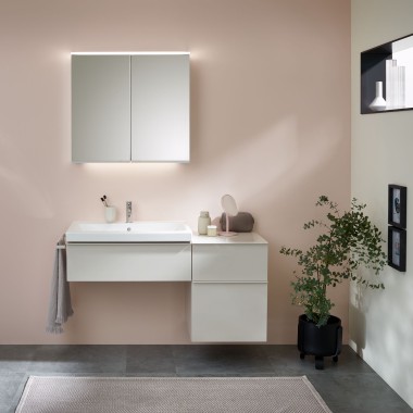 Pesupaikka, jossa on Geberitin kylpyhuonekalusteet, pesuallas ja peilikaappi pastellivärisellä seinällä