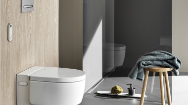 Geberit AquaClean Mera Comfort -pesu-wc-istuimen mukana tulee kaukosäädin. Kuvassa myös Sigma50 -huuhtelupainike (© Geberit)