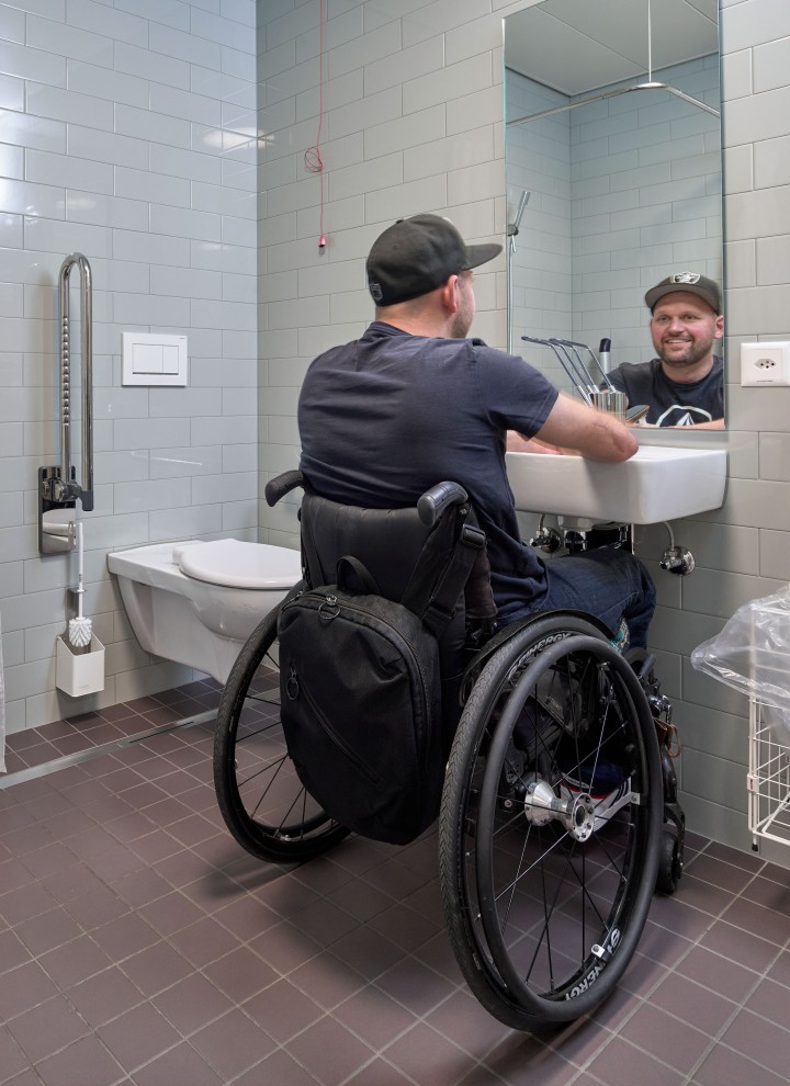 Peter Roos pyörätuolissa pesuallasalueella esteettömässä kylpyhuoneessa (© Ben Huggler)