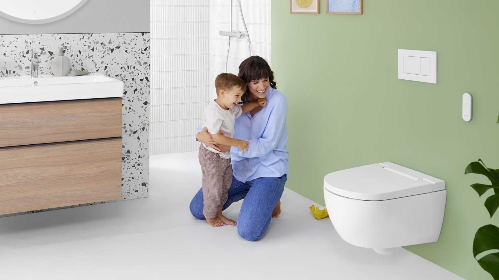 Nainen ja lapsi Geberit AquaClean Alba -pesu-WC:n äärellä. Nainen ja lapsi Geberit AquaClean Alba -pesu-WC:n äärellä.