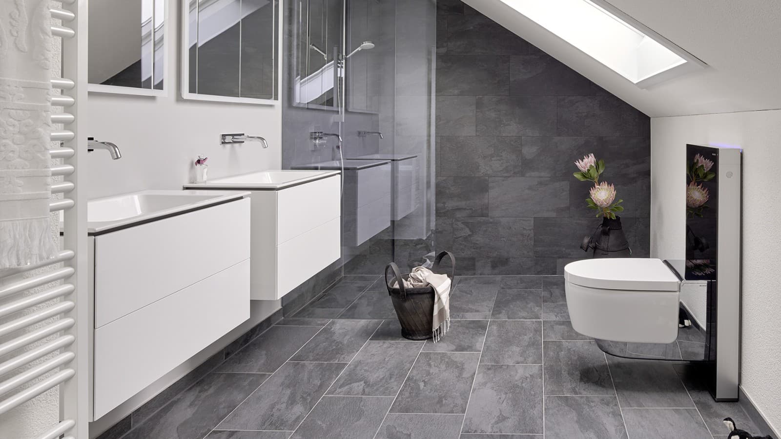 Kylpyhuone, jossa on vinokatto ja Geberit ONE -kylpyhuonesarjan tuotteita sekä Geberit AquaClean Monolith-moduulilla Kylpyhuone, jossa on vinokatto ja Geberit ONE -kylpyhuonesarjan tuotteita sekä Geberit AquaClean Monolith-moduulilla