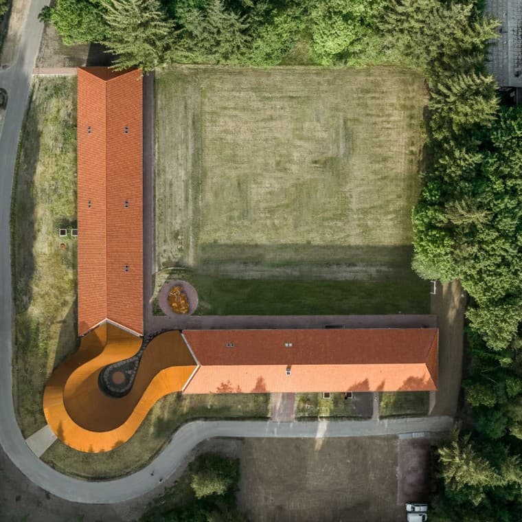 Ylhäältä avautuva näkymä näyttää pyöreänmuotoisen uuden rakennuksen, joka yhdistää kaksi historiallista tiilikattoista rakennusta. (© R_Hjortshoj) Ylhäältä avautuva näkymä näyttää pyöreänmuotoisen uuden rakennuksen, joka yhdistää kaksi historiallista tiilikattoista rakennusta. (© R_Hjortshoj)